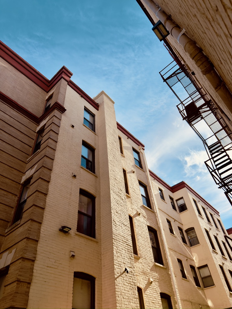 Looking up at buildings and a fire escape against a blue sky